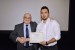 Dr. Nagib Callaos, General Chair, giving Mr. Osman Toker an award certificate in appreciation for his presentation oriented to inter-disciplinary communication entitled: "Performance Analysis of the Communication Protocol in VANETs."